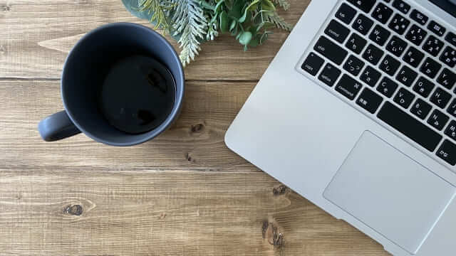テーブルに置かれたPCとコーヒーカップ