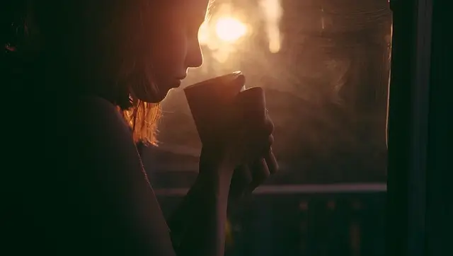 夕暮れにコーヒーを飲んでいる女性
